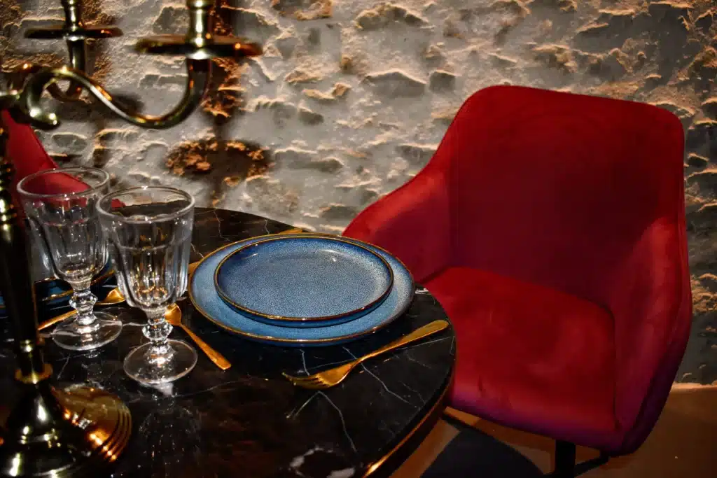 Une table avec un chandelier, des couverts et des assiettes et une chaise rouge en velours