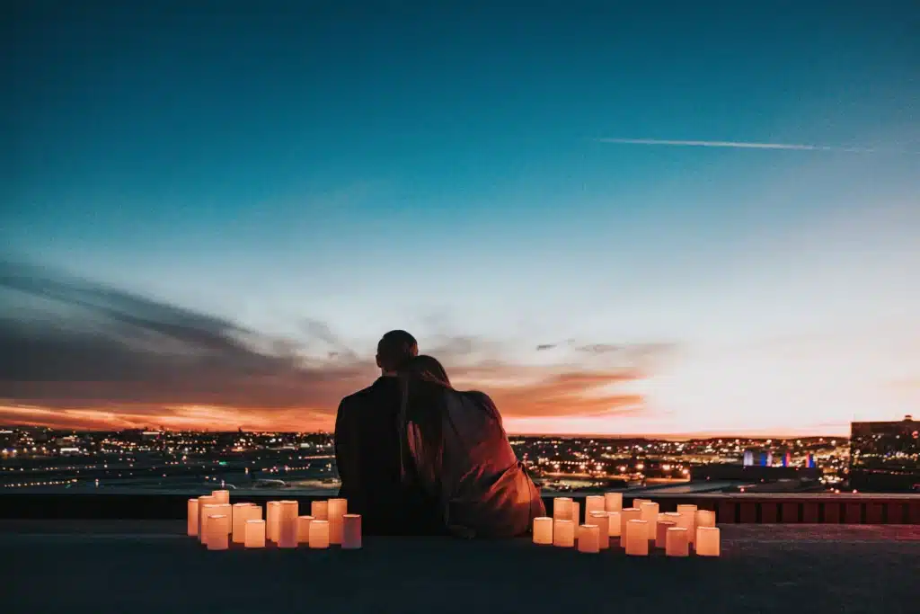 Le langage de l'amour, un couple assis face au coucher du soleil et des bougies autour d'eux
