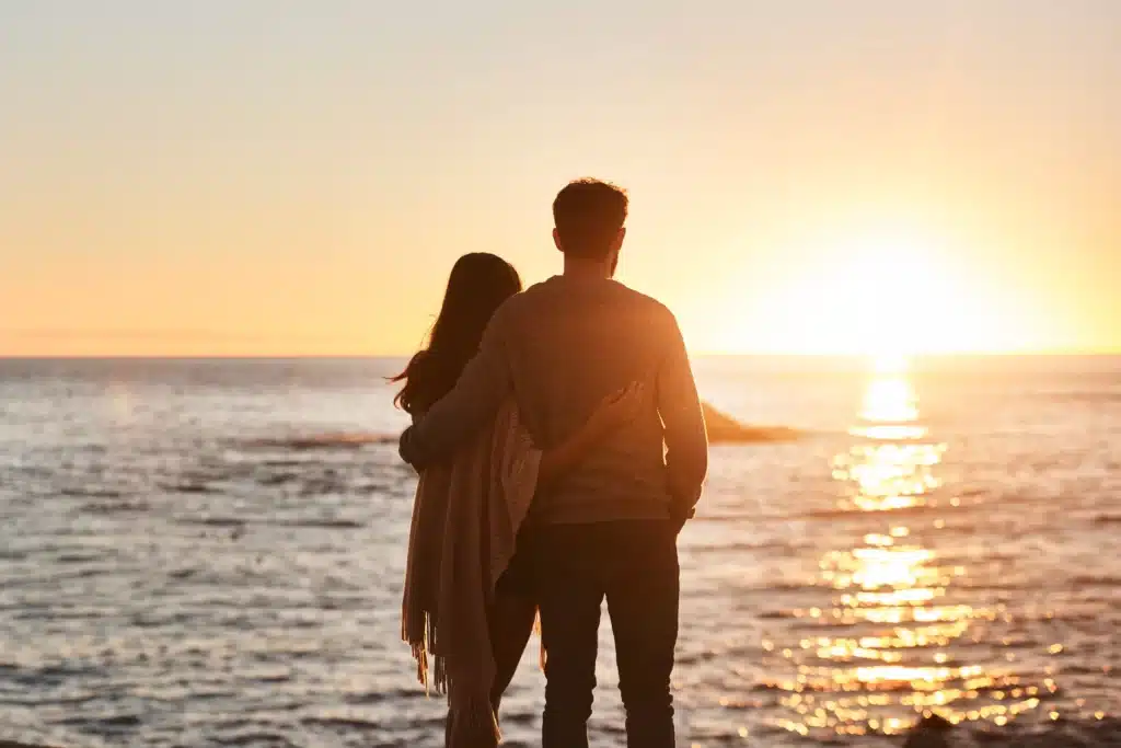 moment romantique entre amoureux devant un coucher de soleil face à l'océan